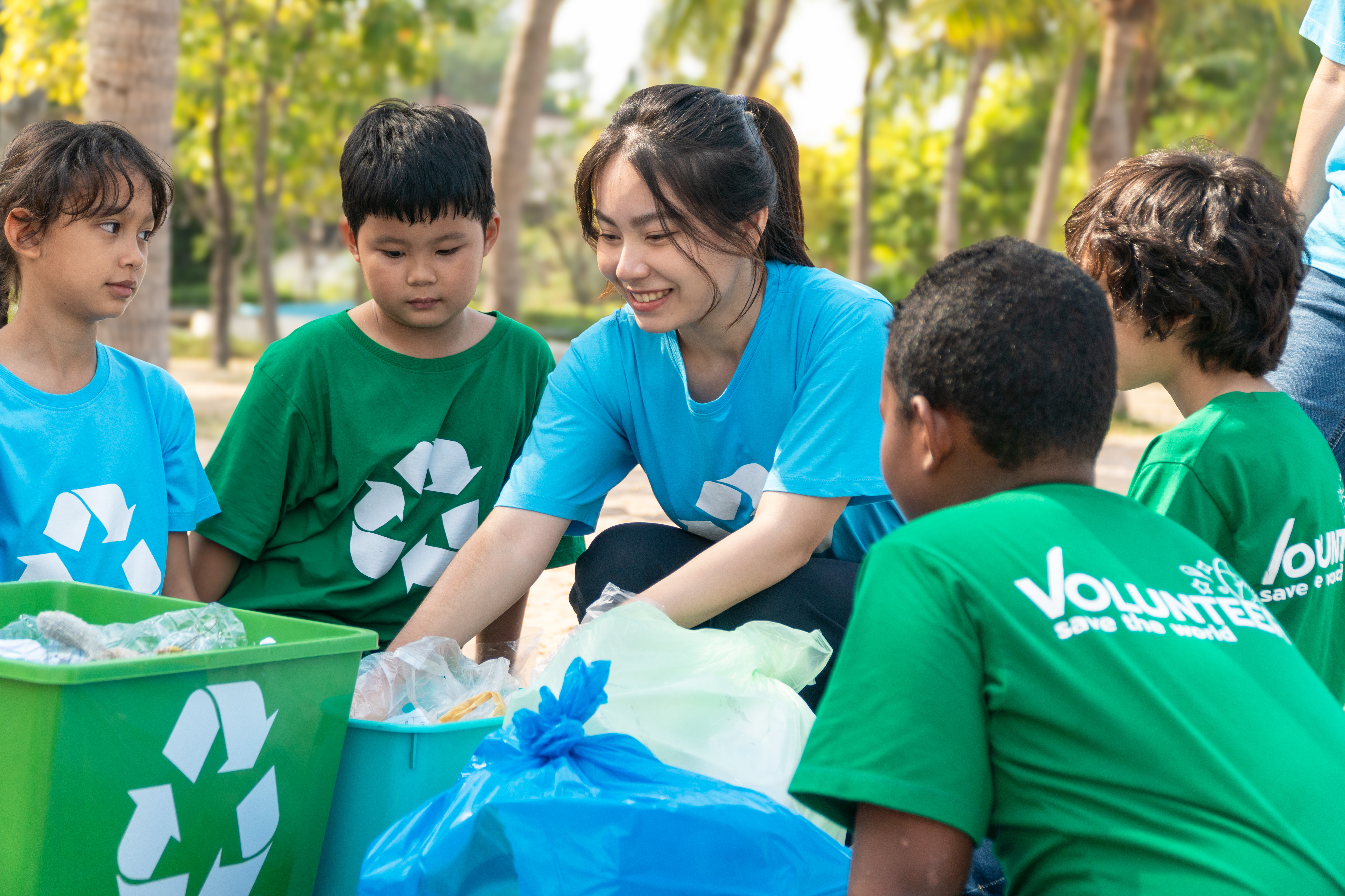 Group of kids school volunteer charity with garbage bags cleaning up on the beach.
